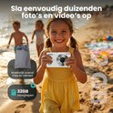 Lachend meisje met KIEKZ 64MP camera op het strand, met op de achtergrond kinderen en een 32GB SD-kaart.