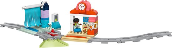 Station met klok, balie, winkel en figuur, verbonden met treinrails, wasstraat en verkeerslicht.