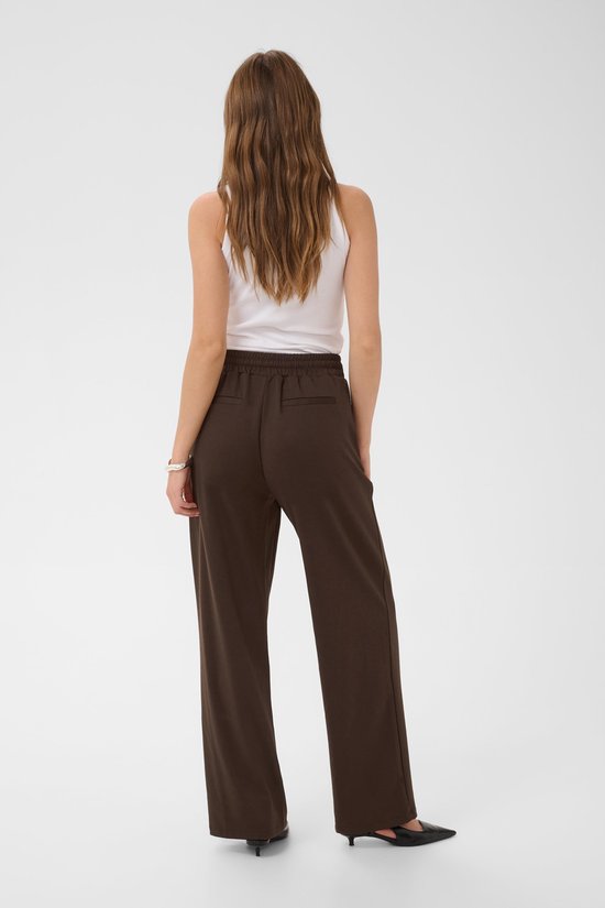 Achterkant model in bruine wijde broek met strikceintuur.