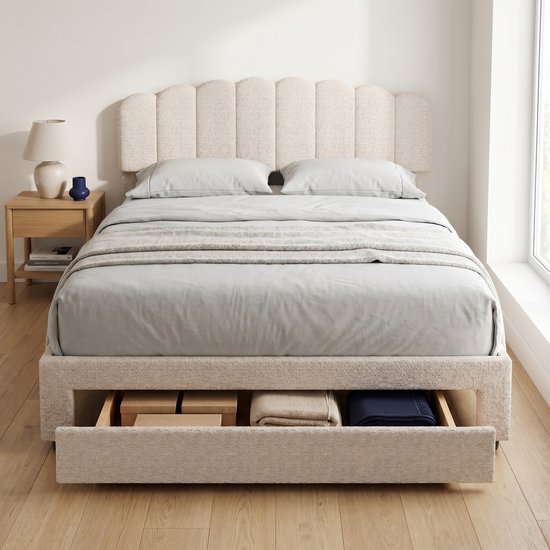 Gestyled beige teddy stof tweepersoonsbed met schelpvormig hoofdbord, opgemaakt met lakens, dekens en kussens. Lade is uitgeschoven en toont opbergruimte.