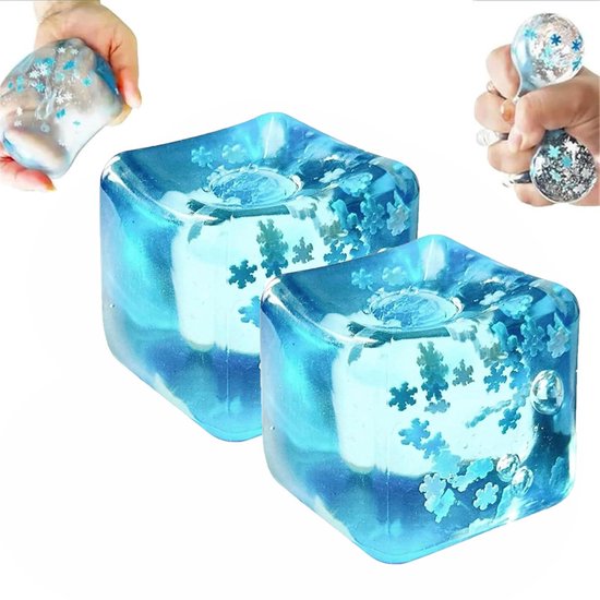 Twee blauwe, vierkante squishies met witte kernen en glitterende sneeuwvlokken. Op de achtergrond knijpen handen een squishy.