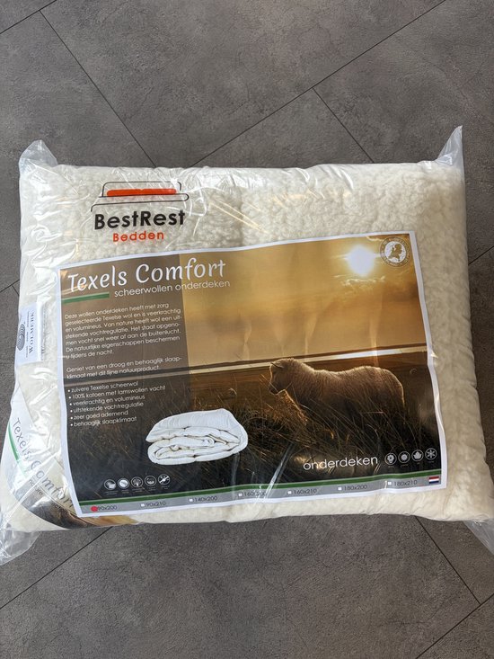 Couverture Texels Comfort en laine de mouton dans son emballage transparent. La couverture est de couleur crème et présente une texture épaisse et laineuse.