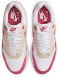 Witte Nike sneakers met roze en beige accenten, zichtbare Air unit en roze Nike Air logo's op de tong.