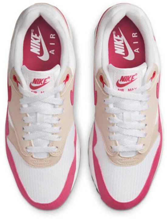 Witte Nike sneakers met roze en beige accenten, zichtbare Air unit en roze Nike Air logo's op de tong.