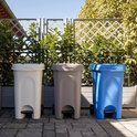 Witte, grijze en blauwe kliko's met pedaal en wielen op een terras.