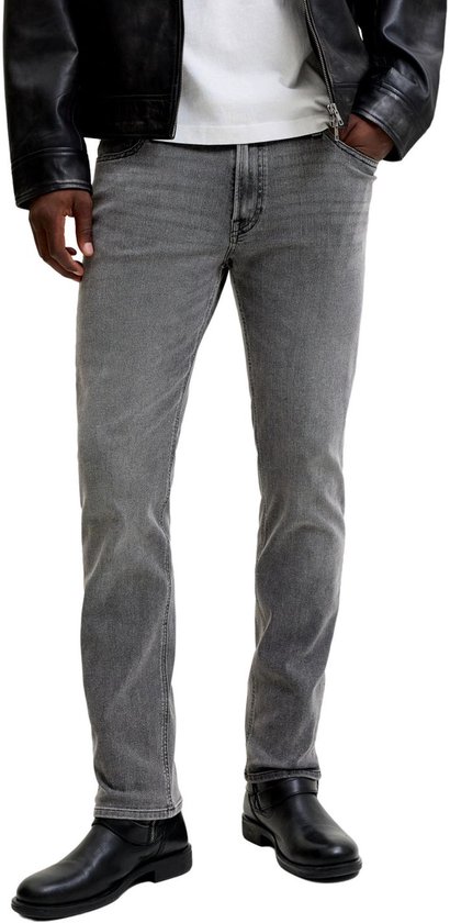 Detail van grijze jeans met zwarte laarzen.