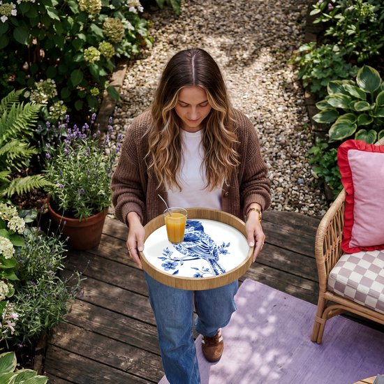 Rond houten dienblad met Delfts blauw vogeldecor, gedragen door een vrouw.