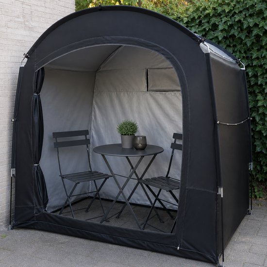 Zwarte opslagtent met een tuinset: tafel, twee stoelen en een plant.