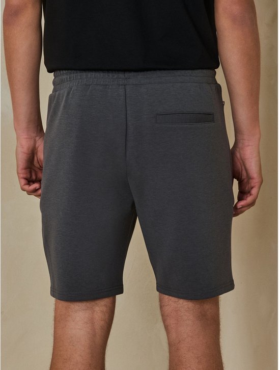 Achterkant van een grijze jersey short met elastische tailleband en achterzak.