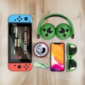 Groene Minecraft draadloze koptelefoon met Creeper-print, naast een Nintendo Switch, smartphone en zonnebril.