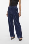 Model in een donkerblauwe, glanzende, wijde broek met plooien.