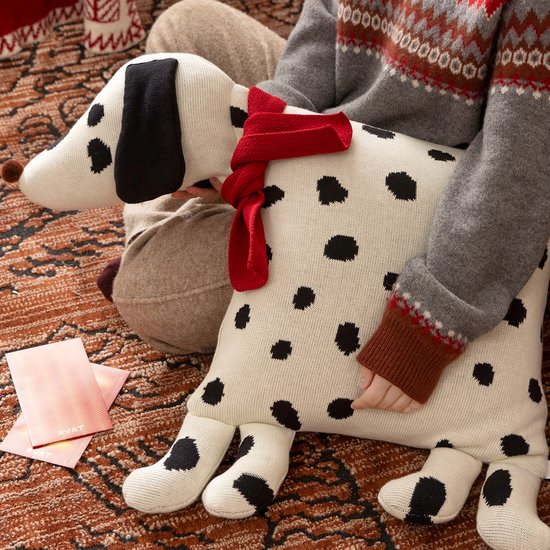 Wit sierkussen Dalmatiër met zwarte vlekken en rode sjaal, vastgehouden door een kind.