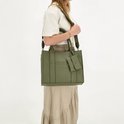 Model met natuur groen tote bag met 'CHARM LONDON' in reliëf en bijpassend etui, gedragen met schouderband.