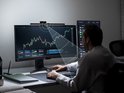 Man die naar een computerkabel kijkt met de BenQ ScreenBar Halo erop gemonteerd, met lichtstralen die het scherm verlichten.