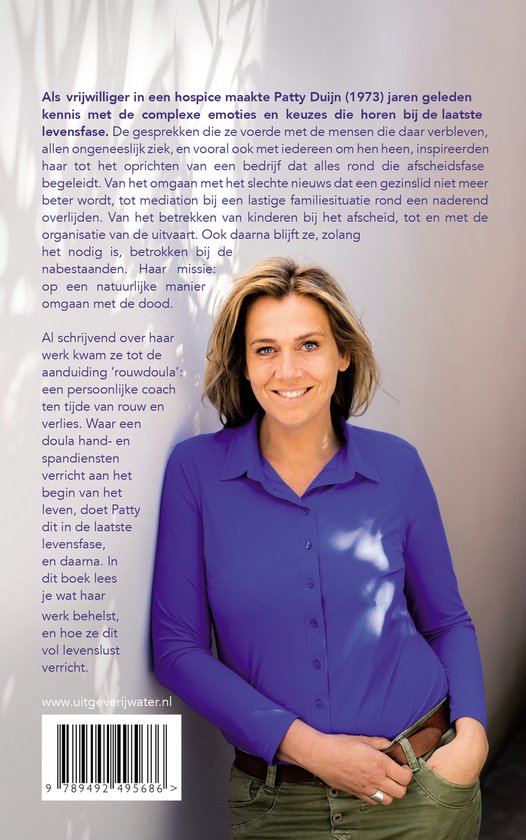 Een lachende vrouw met blond haar, Patty Duijn, draagt een blauw overhemd en jeans.