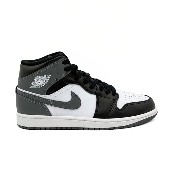 Een witte Nike Air Jordan 1 Mid sneaker met zwarte en grijze accenten.