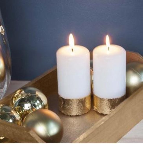 Twee brandende witte kaarsen met gouden onderkant in een houten schaal, omringd door gouden kerstballen.