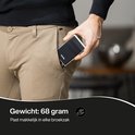 Man stopt slanke, zilverkleurige en zwarte Hëndig pasjeshouder in broekzak.