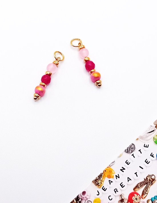 Twee oorbedeltjes met roze en fuchsia kralen van natuursteen aan gouden ringetjes.