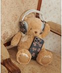 Bruine teddybeer met koptelefoon, vasthoudend aan een telefoonhoesje met bruine teddyberen en zwarte strikjes op grijs ruitje.