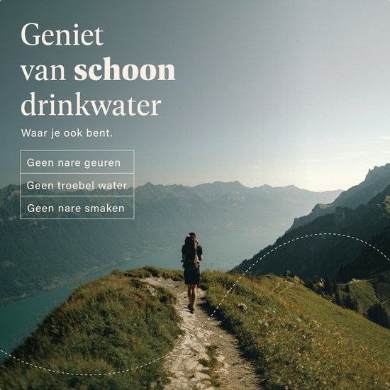 Vrouw met rugzak loopt op een bergpad met uitzicht op een bergmeer en de bergen.