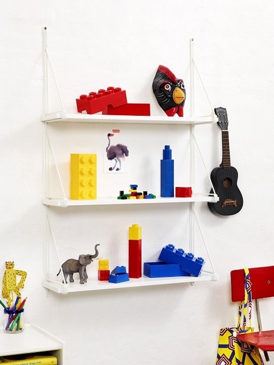 Een witte wandplank met diverse LEGO items: rode stenen, een beeldje van een struisvogel, blauwe flessen, en een zwarte gitaar.