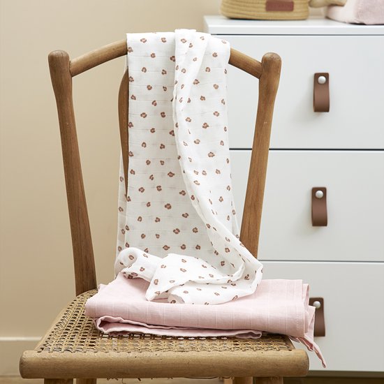 Zachtroze hydrofiele luier en witte luier met panterprint op een houten stoel.