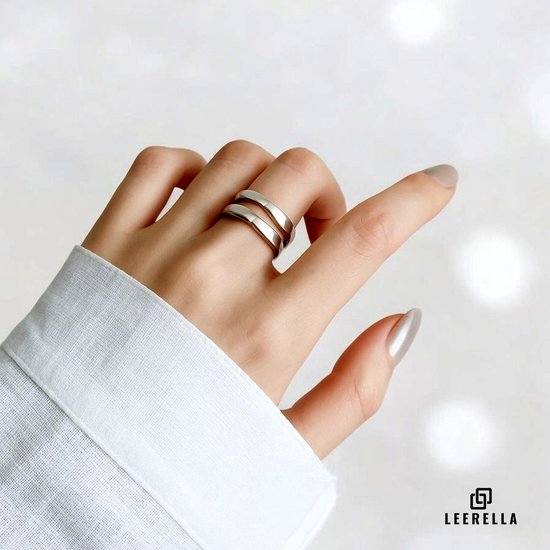 Dameshand met zilverkleurige ring met twee overlappende banden, gedragen aan de wijsvinger.
