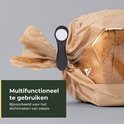 Een zwarte knijper klemt een bruine papieren zak met brood dicht.