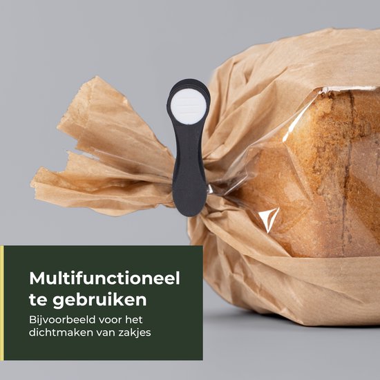 Een zwarte knijper klemt een bruine papieren zak met brood dicht.