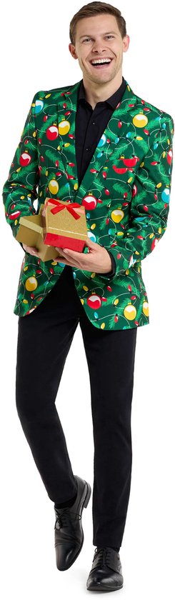 Man in groen colbert met opdruk van kerstlampjes, kerstballen en dennentakken. Hij houdt twee gouden cadeauboxen vast.
