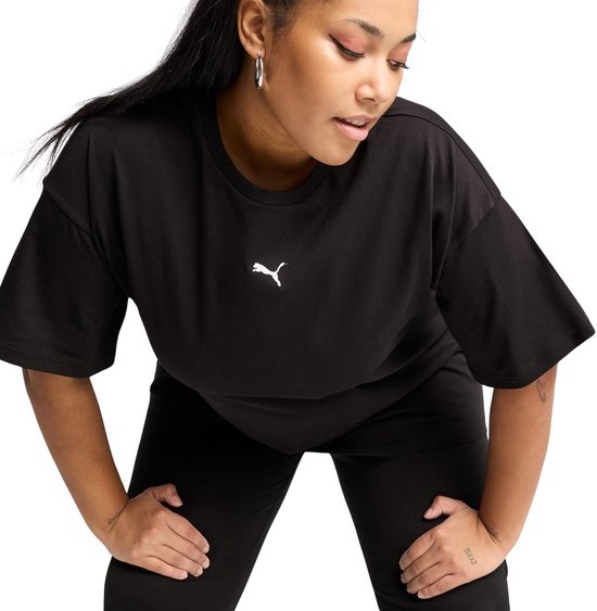 Een vrouw met lange zwarte haren draagt een zwarte oversized T-shirt met Puma logo.