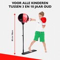 Jongen met rode handschoenen slaat op rode/zwarte boksbal, hoogte 80-106cm. Witte achtergrond.