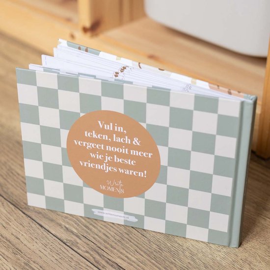 Vriendenboekje met schaakbordpatroon en cirkelvormige tekst. 'Vul in, teken, lach & vergeet nooit meer wie je beste vriendjes waren!'