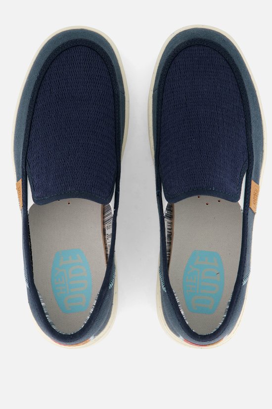 Mocassins HEYDUDE bleus en textile avec une semelle blanche. L'intérieur montre le logo 'HEY DUDE'.