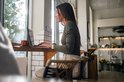 Vrouw met lange donkere haren draagt een zwarte smartwatch aan haar linkerpols terwijl ze op een laptop typt.