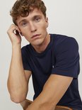 Close-up van een donkerblauw T-shirt met korte mouwen en het geborduurde '&' logo op de borst.