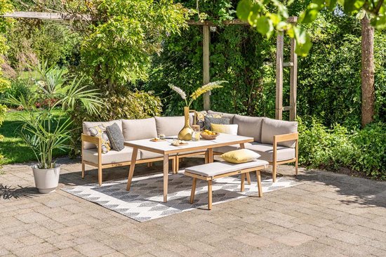 Tuinmeubelen op een terras met grijs-wit geometrisch vloerkleed. Zithoek met tafel en bankje.