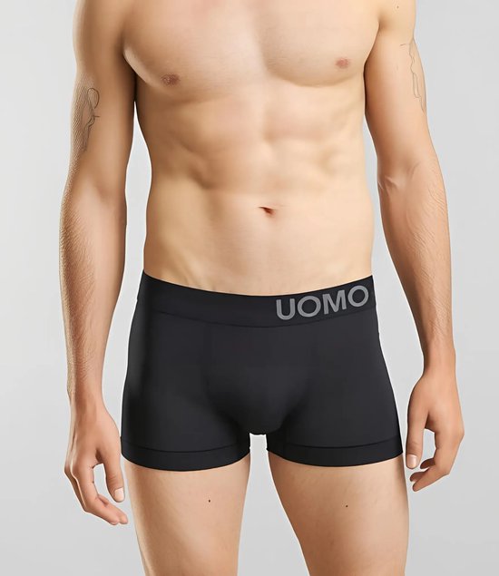Zwarte boxer met grijze UOMO-logo op de tailleband, gedragen door een man.