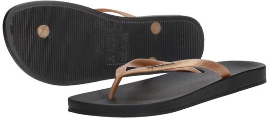 Zwarte Ipanema slippers, één ondersteboven, met gouden bandjes.