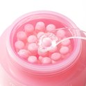 Medicube PDRN Pink Collagen Capsule Cream: close-up van roze capsules in de crème, met een spatel die een capsule oppakt.
