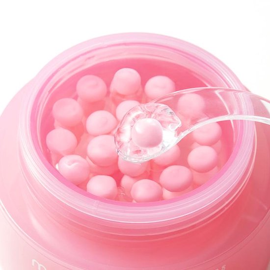 Medicube PDRN Pink Collagen Capsule Cream: close-up van roze capsules in de crème, met een spatel die een capsule oppakt.