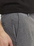 Close-up van de zakken van een grijze broek met fijne structuur.