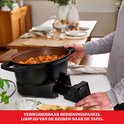 Man haalt een verwijderbaar bedieningspaneel uit een zwarte multicooker met een stoofschotel erin.
