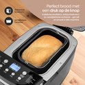 Goudbruin brood in een broodvorm binnenin een open zwarte broodmachine. Bedieningspaneel met instellingen.
