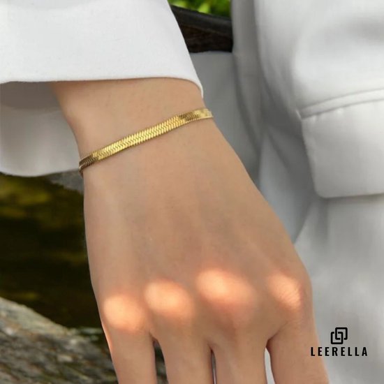 Arm van een vrouw met een goudkleurige slangarmband met schakels aan.