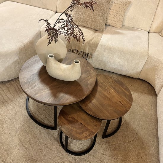Drie ronde salontafels van mangohout met zwart metalen onderstel, gestyled met decoratieve vazen.