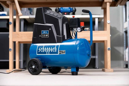 Scheppach compressor met 24L tank, 1.5 PK, blauwe tank en zwarte kap. Met wielen en werkbank op achtergrond.