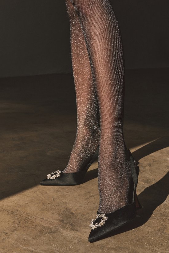 Voeten in zwarte schoenen en glinsterende panty