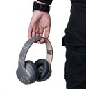 Hand houdt grijze en gouden PowerLocus P6 koptelefoon met geometrisch patroon vast.